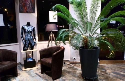 a plant in a room with two chairs and a lamp at Hôtel La Couronne in Marmande