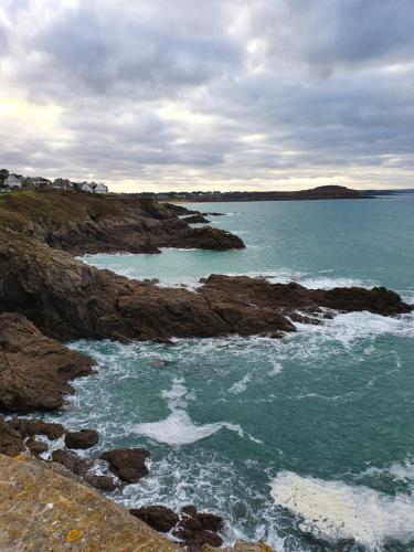 a person standing in the water on a rocky beach at Le Grand Domaine du Rocher in Bonnemain