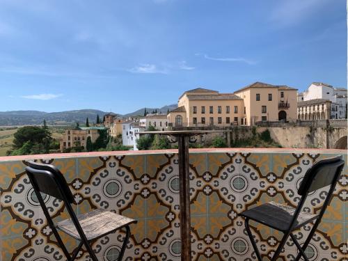two chairs on a balcony with a view of a city at Hotel Don Miguel in Ronda