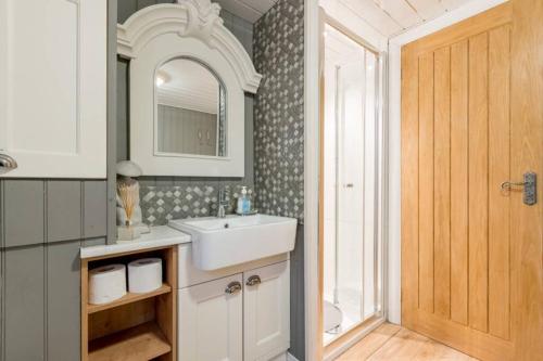 a bathroom with a sink and a mirror at Mistletoe One Luxury Lodge with Hot Tub Windermere in Windermere