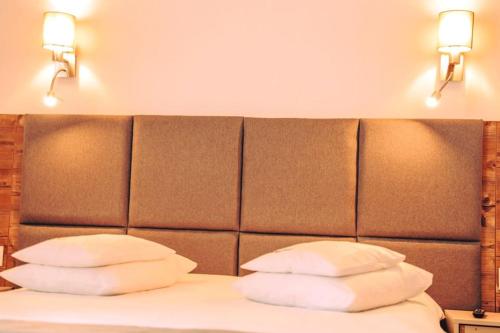 a bed with two pillows and two lights above it at Blumenhof Bucovina in Voronet