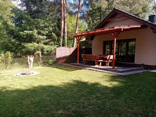 a small house with a picnic table in a yard at Urokliwy Domek nad Brzegiem Jeziora in Lubiatów