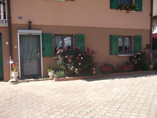 a building with green shutters and flowers in front of it at Gite les Rosiers in Traubach-le-Bas