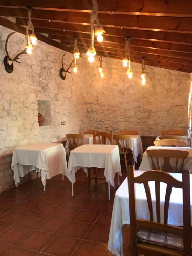 un restaurante con mesas blancas, sillas y luces en Posada La Herradura, en Liermo