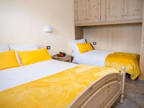 two beds in a room with yellow and white at Residence Pedranzini in Bormio