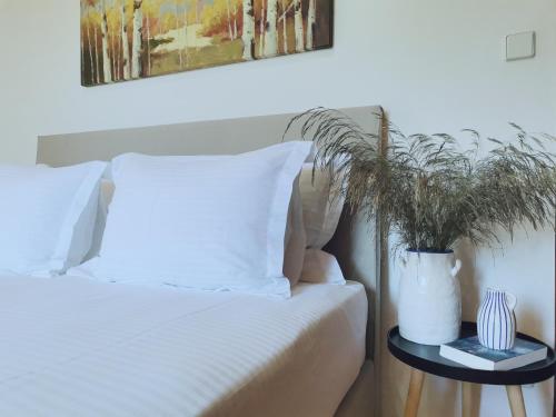 a bed with white pillows and a plant on a table at Spilia Apartments in Stavros