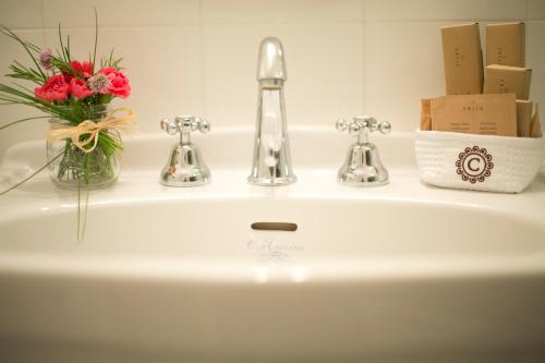 a bathroom sink with a vase of flowers and two faucets at Convento di Acqua Premula in Sellano