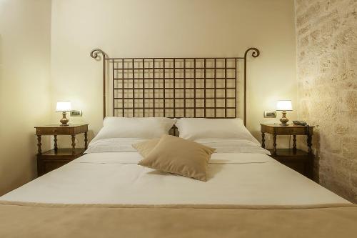 a bed with white sheets and pillows and two lamps at Convento di Acqua Premula in Sellano