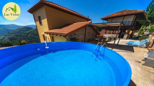 una piscina azul frente a una casa en Las vistas en Cornellana
