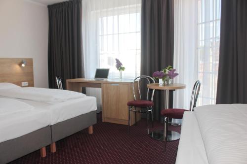 a hotel room with two beds and a desk with a laptop at Hotel Huszcza in Mrągowo