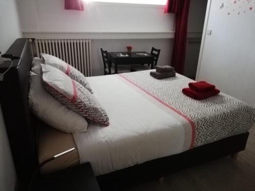 a bed with two pillows and a table in a room at Kokodor in De Haan