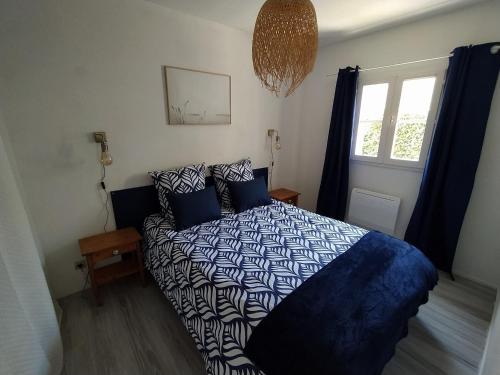 1 dormitorio con 1 cama con edredón azul y blanco en Logement 106 2-4 Personnes 500 m plage classé 2 Etoiles, en Dolus d'Oléron