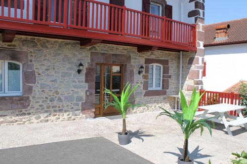 une maison avec un balcon rouge et deux palmiers dans l'établissement Hotel Etchoinia, à Lasse