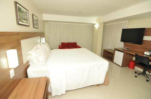 a hotel room with a white bed and a flat screen tv at Holiday Inn Express Belem Ananindeua by IHG in Belém