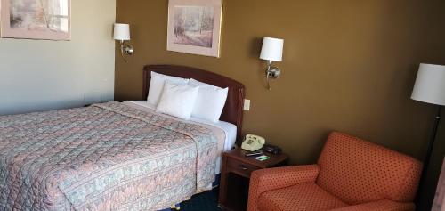 a hotel room with a bed and a chair and a phone at Brooks Motel in Norton
