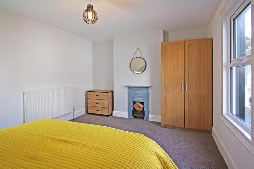 a bedroom with a yellow bed and a fireplace at Bwthyn Cloch Glas in Beaumaris