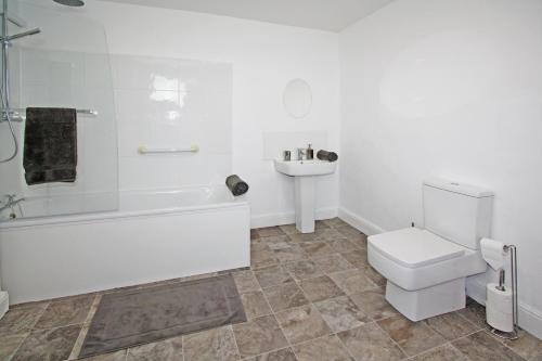 a bathroom with a tub and a toilet and a sink at Bwthyn Cloch Glas in Beaumaris