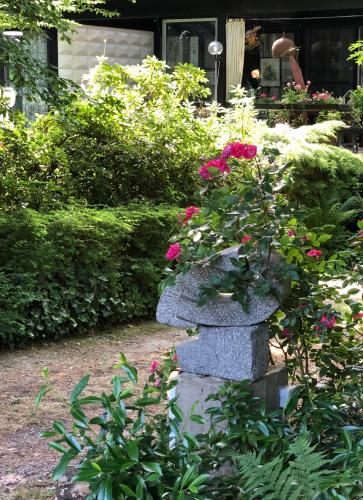 a stone planter with pink flowers in a garden at Linden-Jachthoorn in Lubbeek