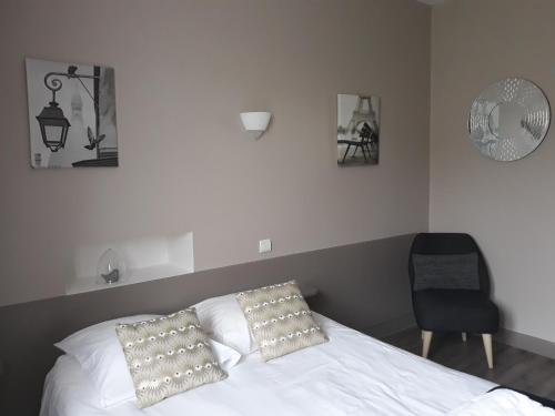 a bedroom with a bed with two pillows and a chair at Hôtel Ambroise in Uzerche