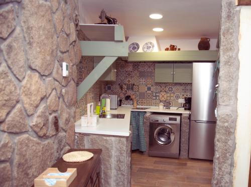 cocina con lavadora y pared de piedra en CASA CUATRO ESQUINAS, en Sotillo de la Adrada