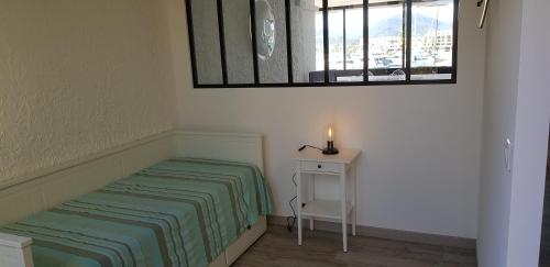 um pequeno quarto com uma cama e uma mesa com uma vela em la galiote em Cogolin