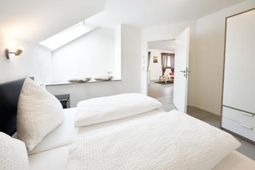 ein weißes Schlafzimmer mit zwei Kissen auf dem Bett in der Unterkunft Ferienwohnung Weißburgunder in Lieser