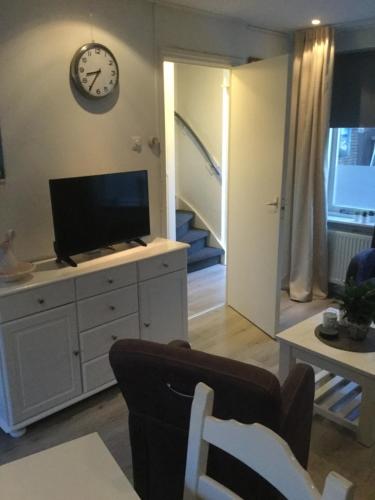 een woonkamer met een tv en een klok aan de muur bij Beach-house27 in Egmond aan Zee