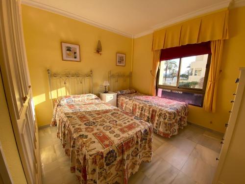 2 camas en una habitación con paredes amarillas y ventana en Apartamento Las Mimosas Beach, en La Cala de Mijas