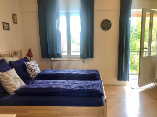 een slaapkamer met een bed met blauwe lakens en een raam bij Sonnhof Ressl in Klosterneuburg