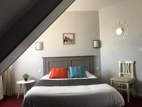 a bedroom with a bed with colorful pillows and a chair at Le Canada in Hermanville-sur-Mer