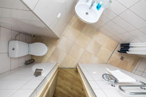 ein weißes Badezimmer mit Waschbecken und Spiegel in der Unterkunft Apartamentai Upė in Šventoji