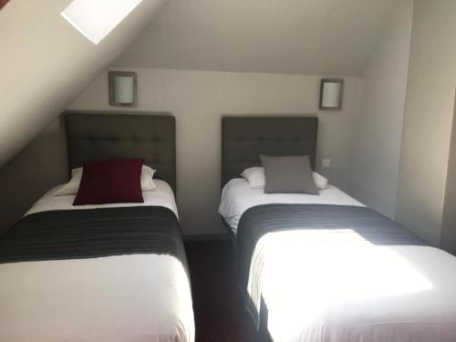 two beds in a small room with white and red at Le Canada in Hermanville-sur-Mer