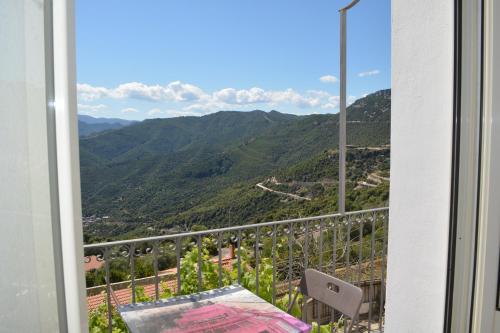 balcone con tavolo e vista sulle montagne di Appartamento Gennirco a Baunei