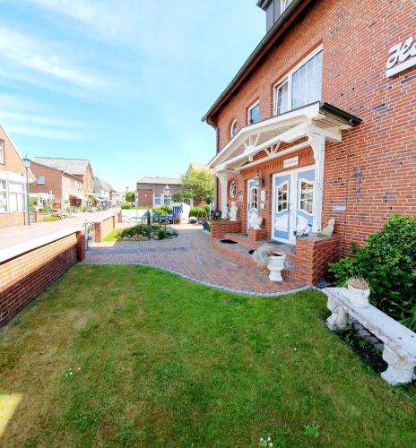 a brick house with a bench in the yard at Hotel-Pension Haus Hubertus in Borkum