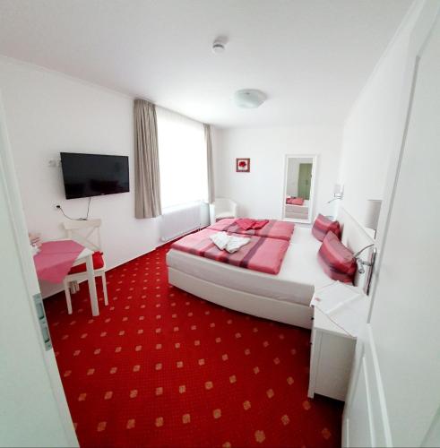 a bedroom with a large bed and a red carpet at Hotel-Pension Haus Hubertus in Borkum