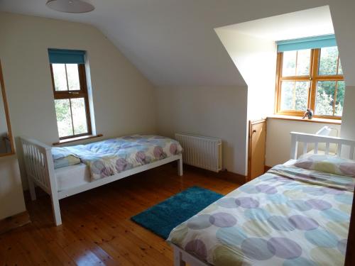 a bedroom with two beds and two windows at The River House in Releagh