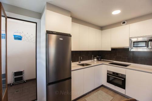a kitchen with white cabinets and a stainless steel refrigerator at Endaneta Berri in Zumaia