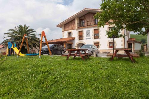 dos mesas de picnic en el césped frente a un edificio en Endaneta Berri, en Zumaia