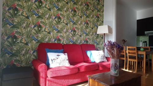 ein rotes Sofa im Wohnzimmer mit Vogeltapete in der Unterkunft Rua Nova Apartment 28 PS4 y Netflix a 200m Catedral in Santiago de Compostela