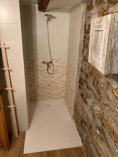 a bathroom with a shower with a stone wall at Casa Marqueso in Figuerola de Orcau