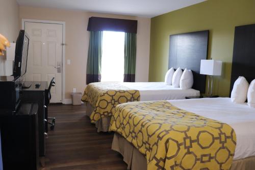 フローレンスにあるBaymont by Wyndham Florence/Muscle Shoalsのベッド2台とデスクが備わるホテルルームです。