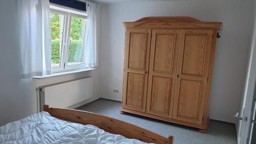 フェーマルンにあるFerienwohnung Erdgeschossのベッドと木製のキャビネットのある寝室