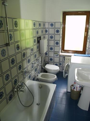 a bathroom with a tub and a toilet and a sink at Appartamenti Katinanna in Alleghe