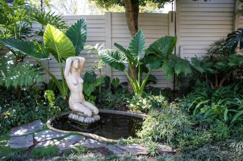 a statue of a woman sitting on a fountain in a garden at 64 on Malabor in Pretoria