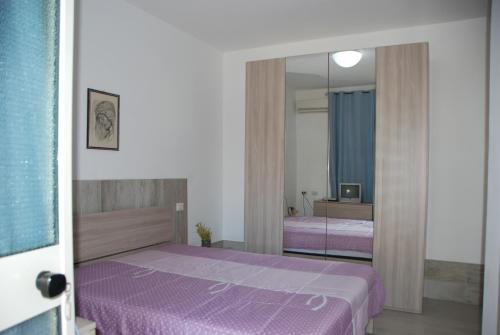 een slaapkamer met een paars bed en een spiegel bij Appartamenti Enza&Giuseppe in Peschici