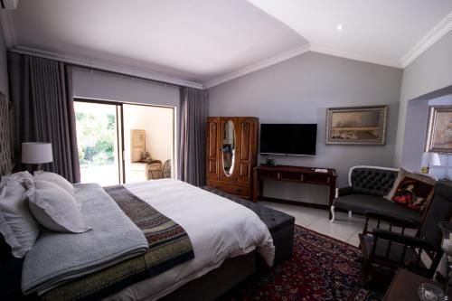 a bedroom with a bed and a chair and a television at 64 on Malabor in Pretoria