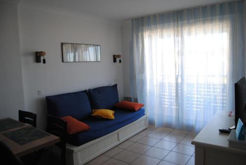 Sofá azul en una habitación con ventana en Agréable T2 balcon et piscine dans résidence bord de mer en Lacanau-Océan