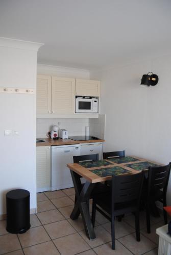 une cuisine avec une table et des chaises et un micro-ondes dans l'établissement Agréable T2 balcon et piscine dans résidence bord de mer, à Lacanau-Océan
