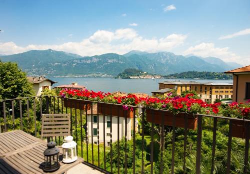 a balcony with red flowers and a view of a lake at Griante suites in Griante Cadenabbia