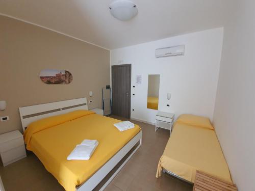Casale Marcalia - bed & breakfast في كوريليانو كالابرو: غرفة نوم بسريرين مع شراشف صفراء